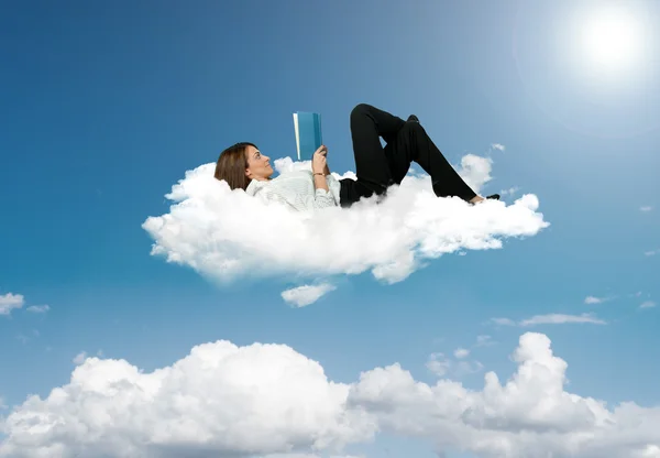 Businesswoman reading a book in a cloud — Stock Photo, Image