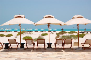 Sunbeds and umbrellas at the Beach of luxury hotel, Abu Dhabi, U clipart