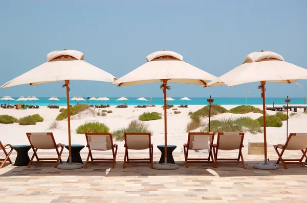 Tumbonas y sombrillas en la playa de hotel de lujo, Abu Dhabi, U — Foto de Stock