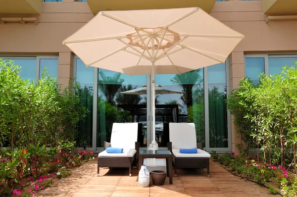 Лежаки и зонтик возле здания роскошного отеля, Дубай, ОАЭ — стоковое фото