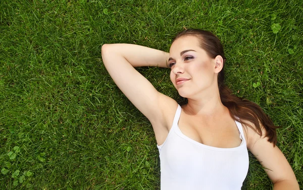 Vacker ung flicka som ligger på gräset — Stockfoto