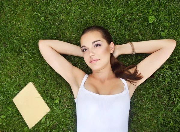 Krásná mladá dívka ležící na trávě — Stock fotografie