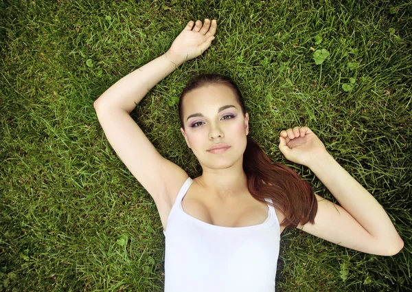 Piękna młoda dziewczyna leżąca na trawie — Zdjęcie stockowe