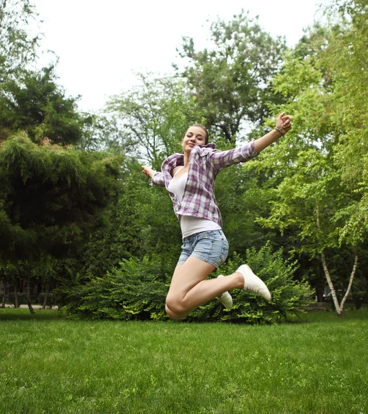Bruna ragazza saltando nel parco estivo — Foto Stock