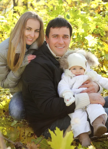 Jovem família feliz no parque de outono — Fotografia de Stock