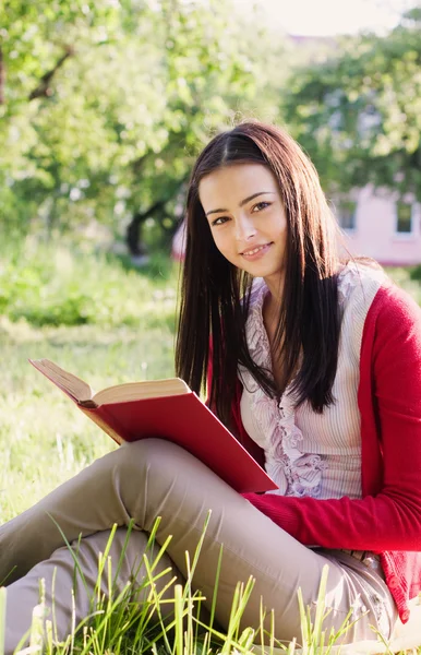 Красивая девушка читает книгу в парке — стоковое фото
