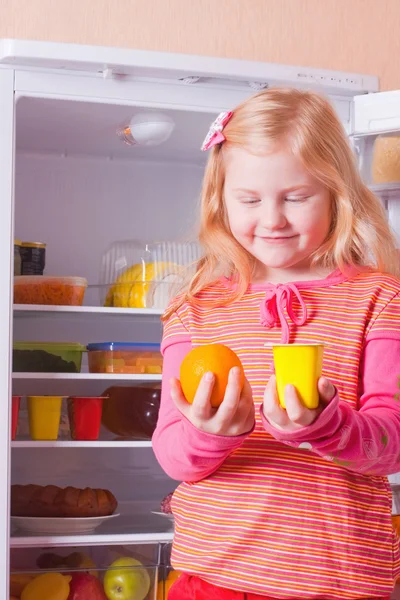 Girl with food on background refrigerator — Stok fotoğraf