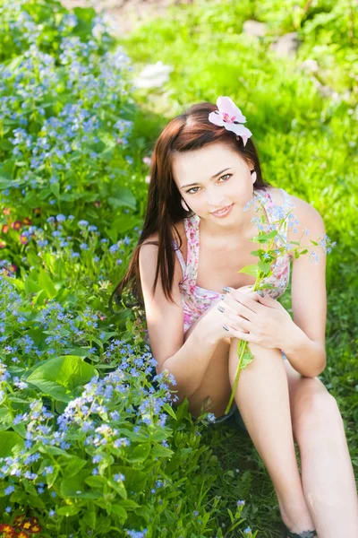 Vacker flicka med blommor i trädgården — Stockfoto