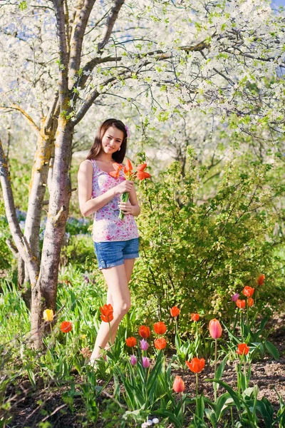 Menina bonita com flores no jardim — Fotografia de Stock
