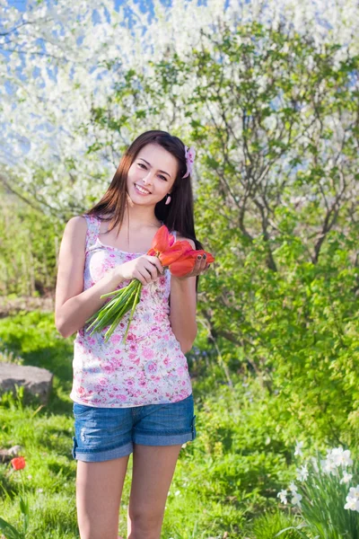Hermosa chica con flores en el jardín — Foto de Stock