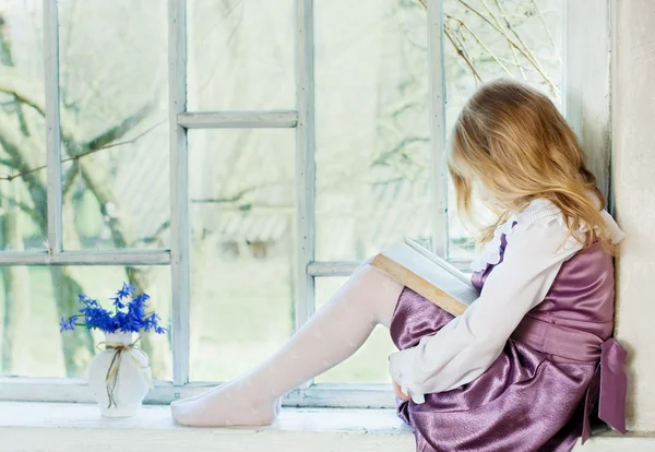 Malá holčička čte knihu uvnitř — Stock fotografie