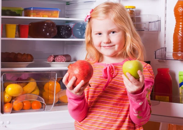 Meisje met vruchten op achtergrond koelkast — Stockfoto