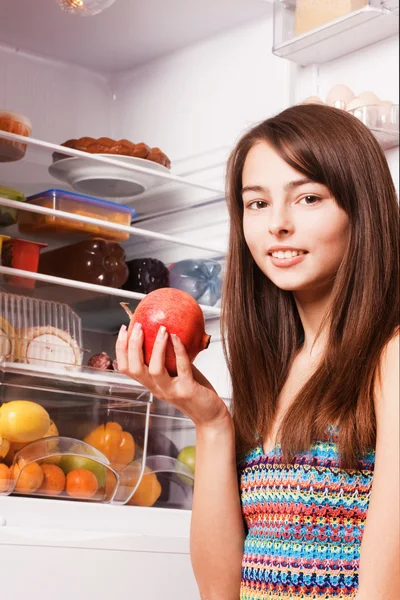 Úsměv holka s granátovým jablkem v kuchyni — Stock fotografie
