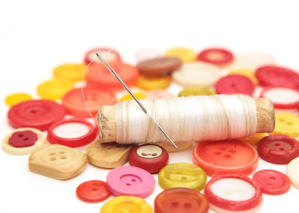 stock image Needle in a spool of thread on the background of the buttons