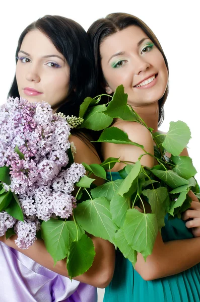 Two girlfriends with flowers of a lilac and green foliage — Stock Photo, Image
