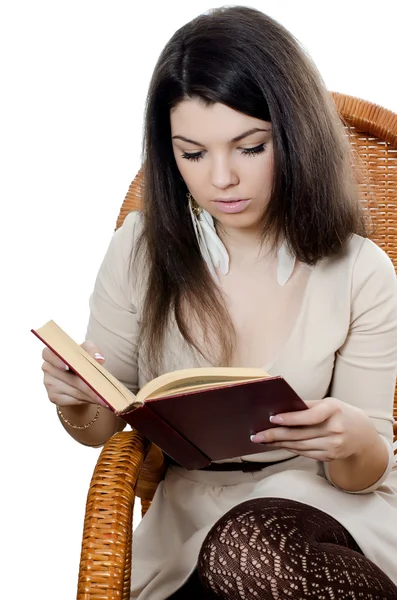 A menina lê o livro em uma poltrona — Fotografia de Stock