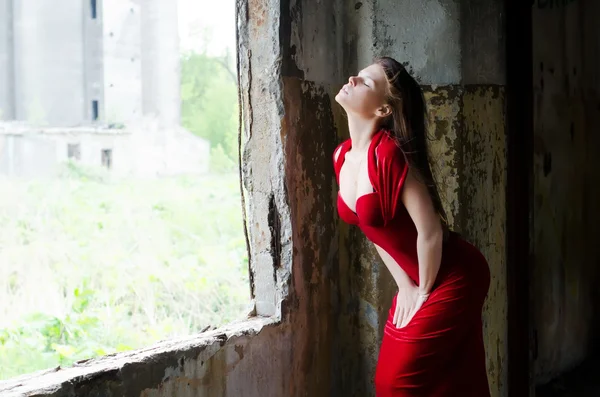 Den vackra flickan i en aftonklänning mot en gammal vägg — Stockfoto