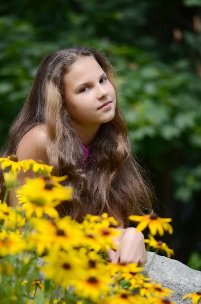 Menina morena bonita relaxante com flores amarelas — Fotografia de Stock