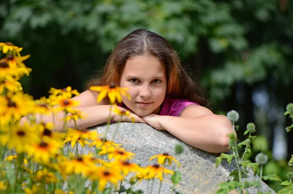 Güzel genç esmer kız sarı çiçekler ile rahatlatıcı — Stok fotoğraf