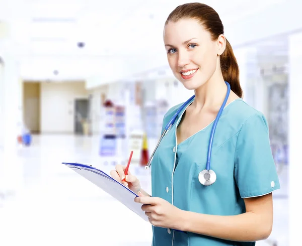 Gülümseyen kadın tıp doktoru bir koridor içinde clipboard ile bir — Stok fotoğraf