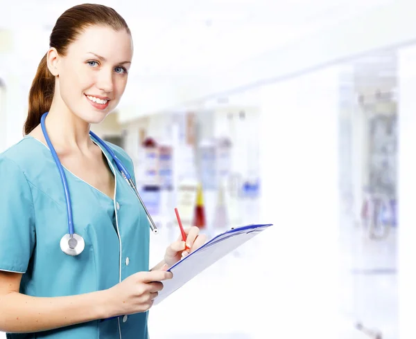 Usmívající se žena lékař s deskami v koridoru — Stock fotografie