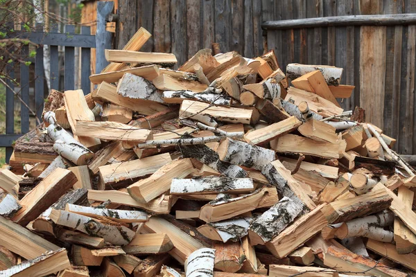 stock image Pile of firewood against old wooden fence