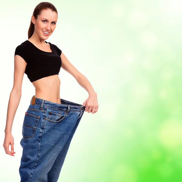 Aantrekkelijke jonge vrouw toont haar oude enorme paar jeans — Stockfoto