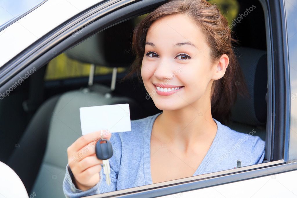 Girl in a car showing a key and an empty white card