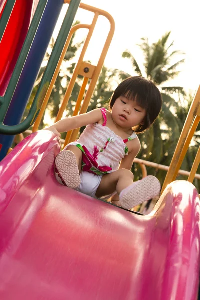 Criança em uma corrediça em playground — Fotografia de Stock