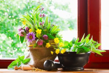 Sack with bouquet of healing herbs and flowers, mortar and pestle on windowsill clipart