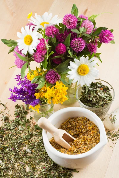 Mortar with healing herbs, bouquet of daisy and clovers on woode — Stock Photo, Image