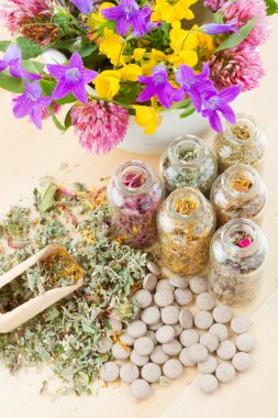 Different healing herbs in glass bottles, flowers bouquet in mort clipart