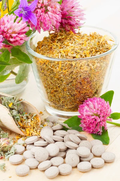 Hierba curativa en taza de vidrio, tabletas, hierbas medicinales —  Fotos de Stock