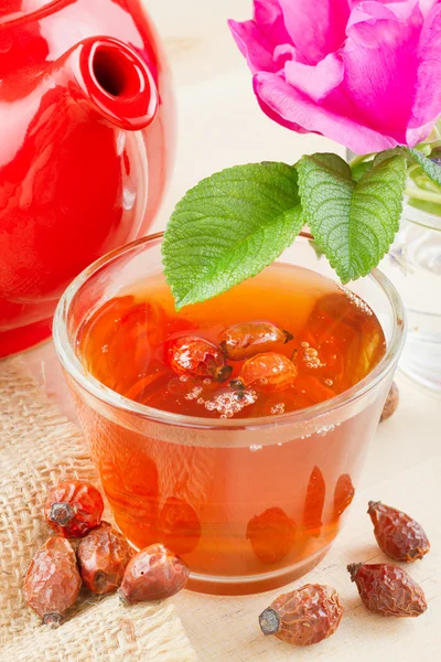 stock image Rose hips tea, red teapot and rose-hip flowers