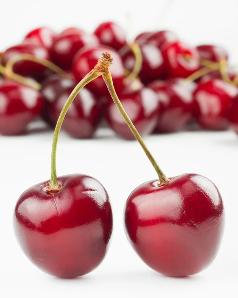 Two red cherries and pile of cherry as background — Stock Photo, Image