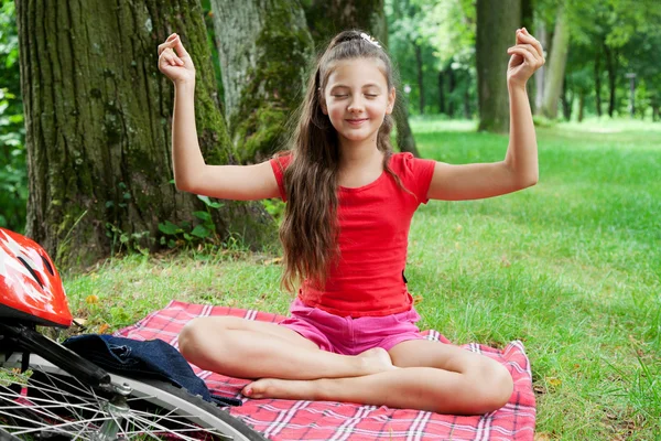 Motorcu kızın rahatlatıcı bir parkta çim üzerinde yoga poz — Stok fotoğraf