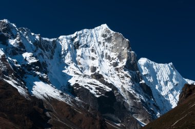 Snowbound mountain range and blue sky in Himalayas clipart