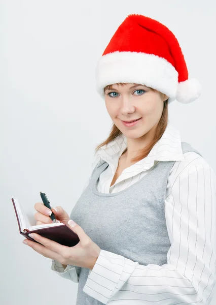 Woman with a notebook in a Christmas hat — Stock Photo, Image