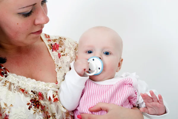 Baby with a pacifier in the arms of mother — Stock Photo, Image