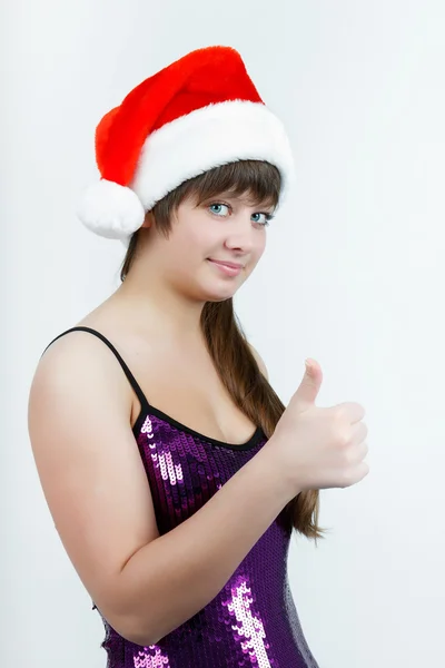 Attractive girl in a Christmas hat with thumb up — Stock Photo, Image