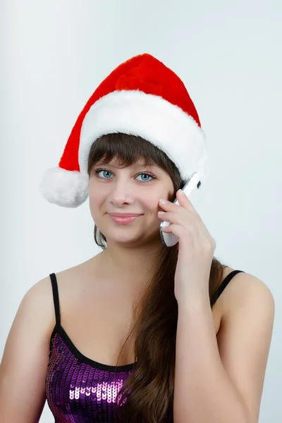 Girl in a Christmas hat talking on a cell phone — Stock Photo, Image