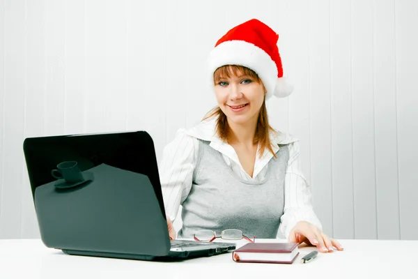Girl in a Christmas hat with a laptop — Stock Photo, Image