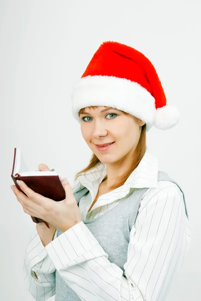 Girl with a notebook in santa hat — Stock Photo, Image