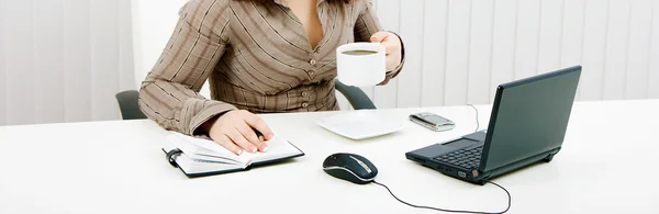 Kvinna dricker kaffe på jobbet med — Stockfoto