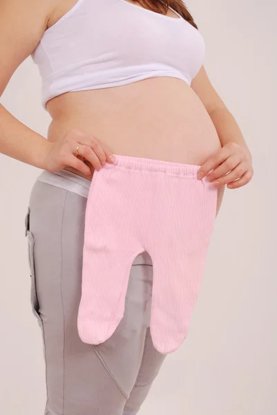 Gravid kvinna med babykläder — Stockfoto