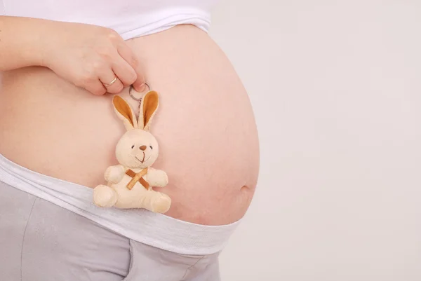 Mulher grávida colocou o brinquedo no estômago — Fotografia de Stock