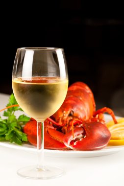 Glass of white wine with cooked lobster clipart