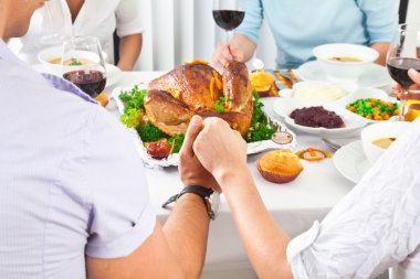 Family members giving thanks to God at festive table clipart