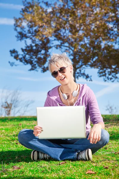 Giovane donna con computer portatile su erba — Foto Stock