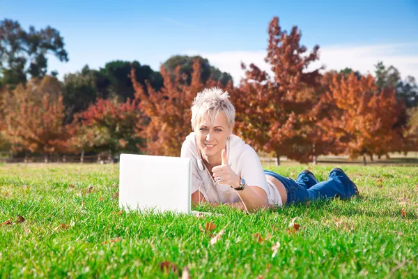 Усміхнена дівчина використовує ноутбук на відкритому повітрі — стокове фото